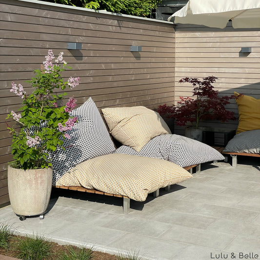 Bunte Outdoor-Sitzkissen nach Maß Cairo aus Olefin-Stoff gestapelt auf einer Gartenlounge